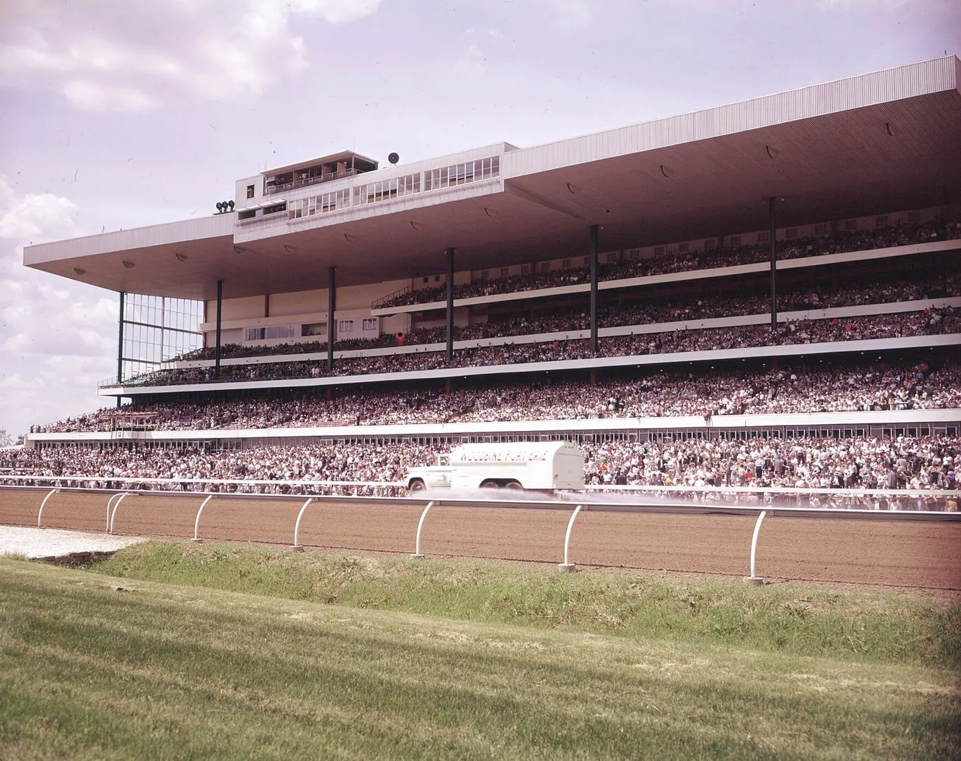 Archival photograph of the Woodbine grandstand from across the grass with a full crowd on the decks