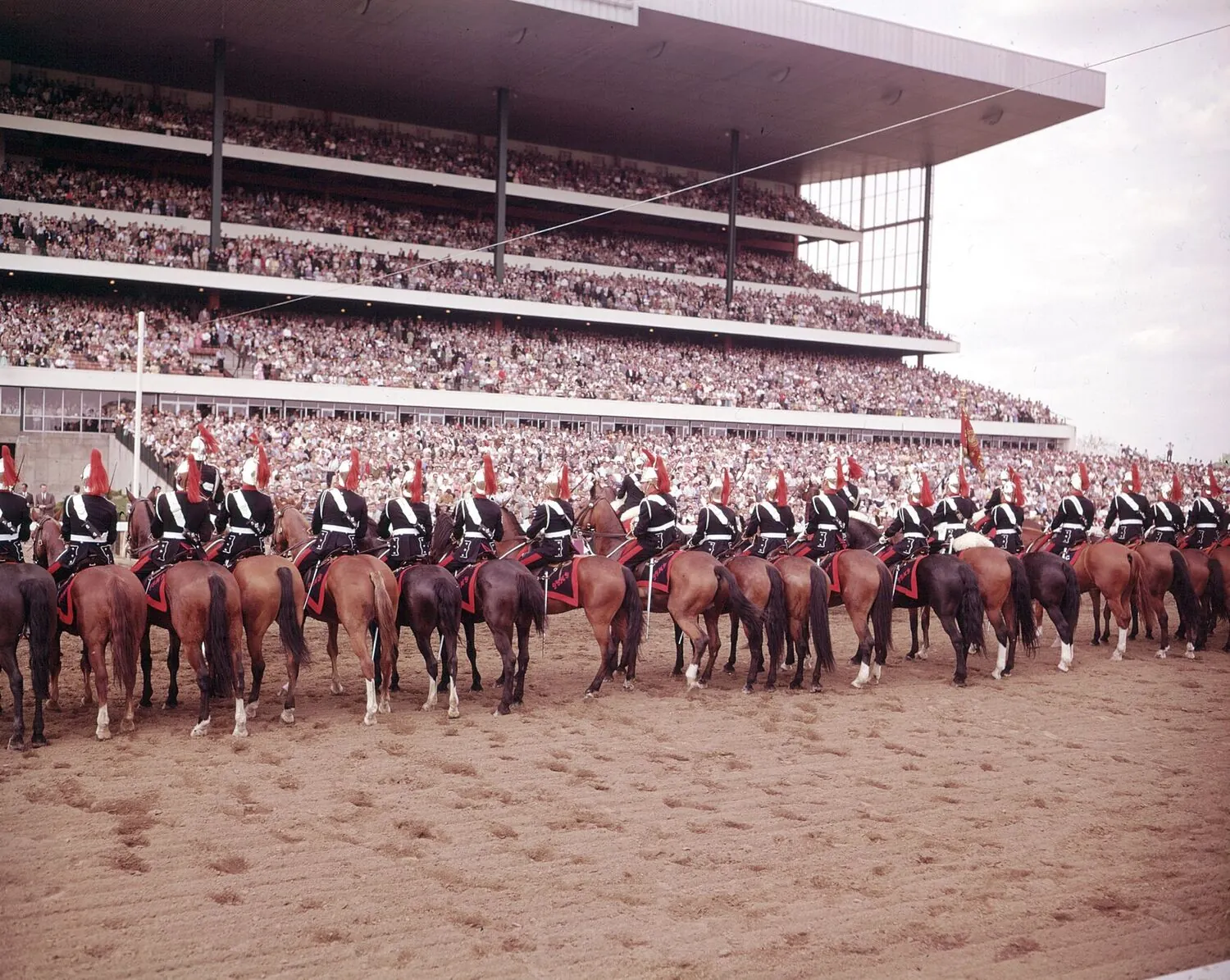 Mounted riders in ceremonial dress lined up on the track in front of a packed Woodbine grandstand