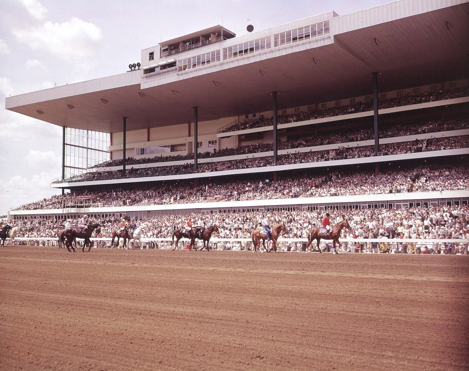 Horses racing down the Woodbine stretch past a crowded three-tier grandstand