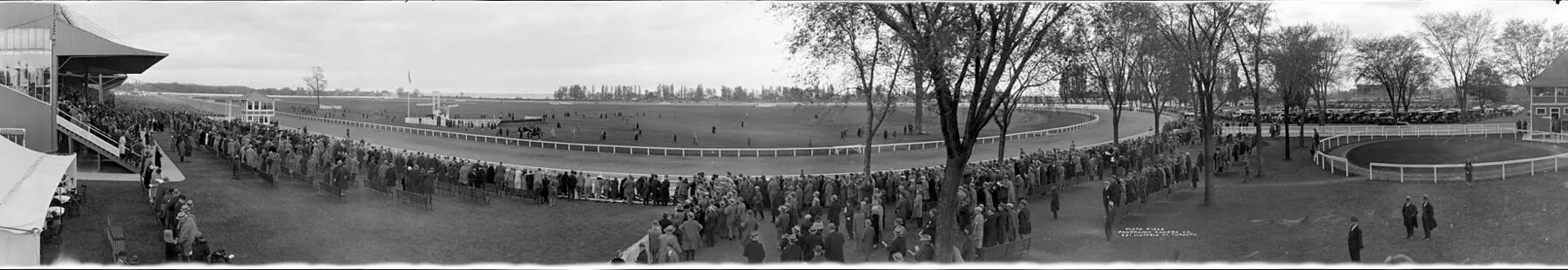 Panoramic black and white photograph of a crowd along the rail at the original Woodbine racetrack in Toronto